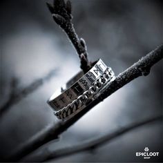 two silver rings sitting on top of a tree branch with the word love written on it