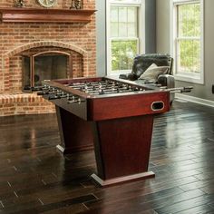 a living room with a foosball table in front of a fire place and couch