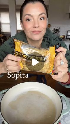 a woman holding up a bag of soup