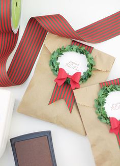 two brown envelopes with red and green ribbons tied around them on a white table