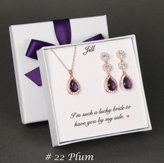 two pieces of jewelry in a gift box with purple ribbon and bow on the side