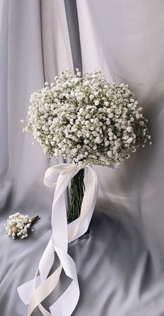 a bouquet of baby's breath tied to a white ribbon on a gray background