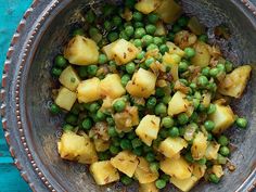 a bowl filled with peas and potatoes on top of a table