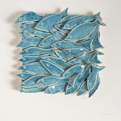 a blue ceramic fish sculpture sitting on top of a white wall