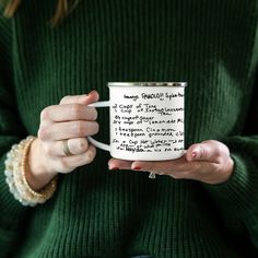 a woman holding a coffee mug with writing on it