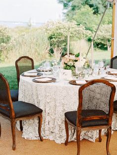 the table is set for two people with plates and glasses on it in front of an open field