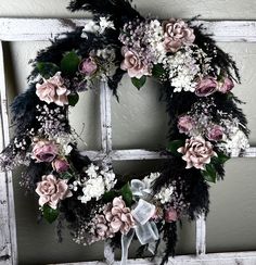 a wreath with flowers and feathers hanging on a door