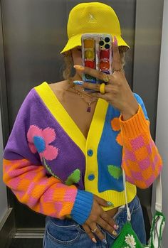 a woman taking a selfie with her cell phone in front of her face and wearing a brightly colored cardigan