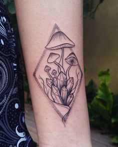 a black and white photo of a mushroom tattoo on the left inner arm, which is surrounded by leaves