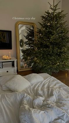 a bedroom with a christmas tree in the corner and a white comforter on the bed