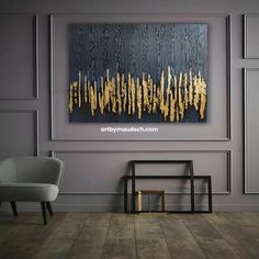 an abstract painting hangs on the wall next to a chair and side table in a modern living room