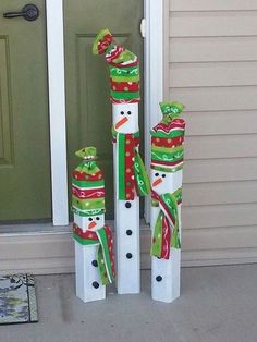 three snowmen standing next to each other in front of a door with christmas decorations on them