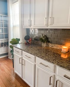 a kitchen with white cabinets and granite counter tops, along with a candle in the center