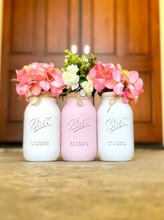 three mason jars with pink and white flowers in them