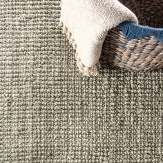 a close up view of a basket on the floor with a white and blue pillow