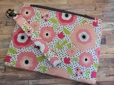 a pink and green flowered purse with polka dots on the bottom is sitting on a wooden floor