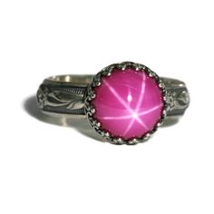 "10mm Lab Created Pink Star Ruby Ring. Fascinating Brilliance! This stone is reminiscent of the vintage “Lindy” synthetic Star Ruby of the 50s thru 70s. The star effect, known as an “asterism”, is more defined in a lab-grown Ruby. They are identical in chemical composition, brilliance, and physical appearance as their natural counterpart, however they have fewer flaws, are not mined from the ground, and are much less expensive. They are an extremely durable stone with a Mohs scale hardness or 9 Star Effect, Blue Star Sapphire Ring, Aventurine Ring, Star Ruby Ring, Star Sapphire Ring, Physical Appearance, Blue Star Sapphire, Crown Vintage, Flower Band