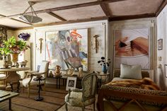 a living room filled with lots of furniture and paintings on the wall next to a table