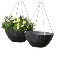 two black hanging planters with daisies in them on white background, side by side