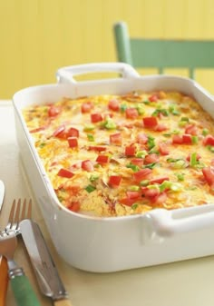 a casserole with tomatoes, green onions and cheese in a white baking dish