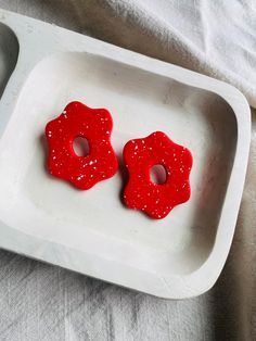 two red donuts sitting on top of a white tray