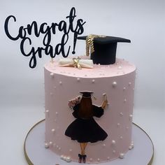 a pink cake with a graduate's cap on top and congratulations written in black