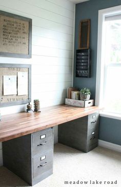 a wooden desk sitting in the middle of a room next to a window with pictures on it