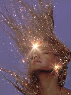 a woman with her hair blowing in the wind and sparkling stars above her head, against a blue sky