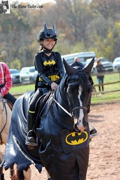 two children dressed up as batman riding horses