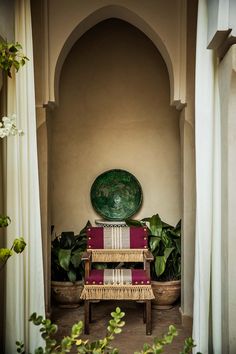 a green plate sitting on top of a table next to a red chair and potted plants