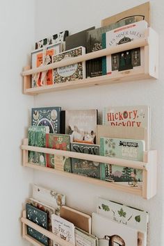 three wooden shelves holding books and magazines on the wall in a room with white walls