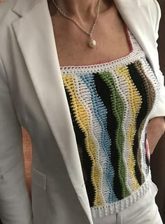 a woman wearing a white blazer with multicolored crochet on it