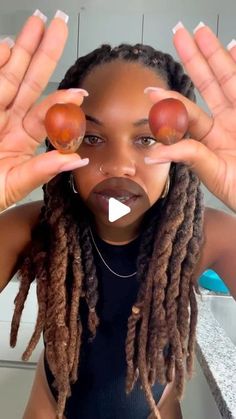 a woman with dreadlocks holding two eggs in front of her face and hands