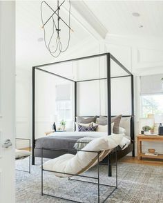 a bedroom with a four poster bed and white walls