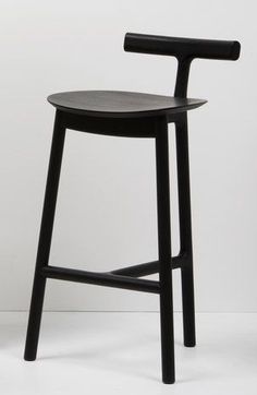 a black wooden stool against a white wall with the seat up and back turned down