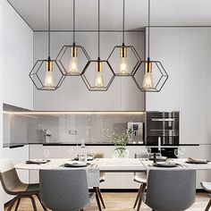 a dining room table with chairs and lights hanging from it's ceiling over the kitchen