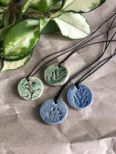 three ceramic pendants with plants on them