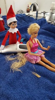 two elf dolls sitting on top of a blue towel next to a hair dryer