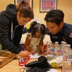 a man and woman are looking at a child's handwritten note on a table