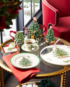 the table is decorated with christmas trees and other holiday decorations, along with plates and cups