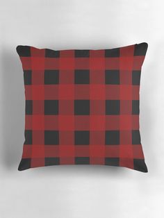 a red and black plaid pillow on a white wall