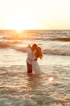 a couple kissing in the ocean at sunset