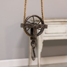 an old fashioned pulley is hanging from a rope in a room with white walls