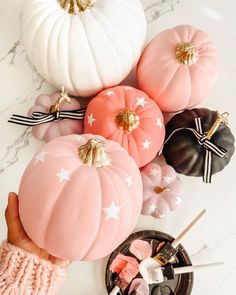 a table topped with pink and white pumpkins next to marshmallows on sticks