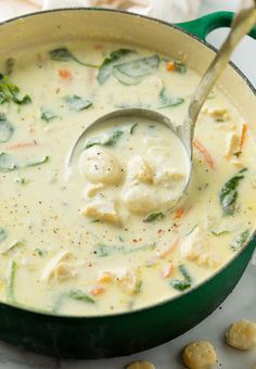 a green pot filled with chicken and dumplings on top of a white tablecloth