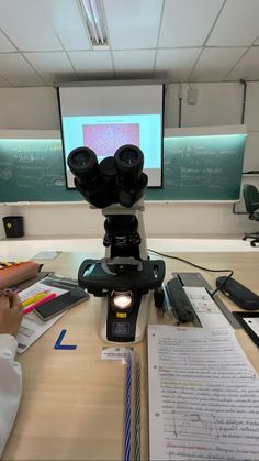 a person sitting at a desk with a microscope