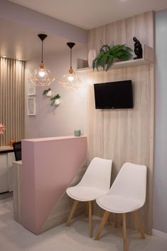 two white chairs sitting next to each other in front of a tv mounted on a wall