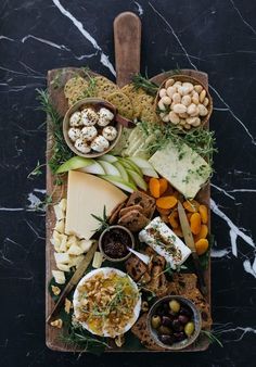 a platter filled with different types of cheeses and crackers on a marble table