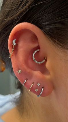 a woman's ear with three different piercings on the top and one behind her ear