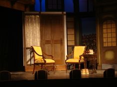 two yellow chairs sitting on top of a stage next to each other in front of a wooden door